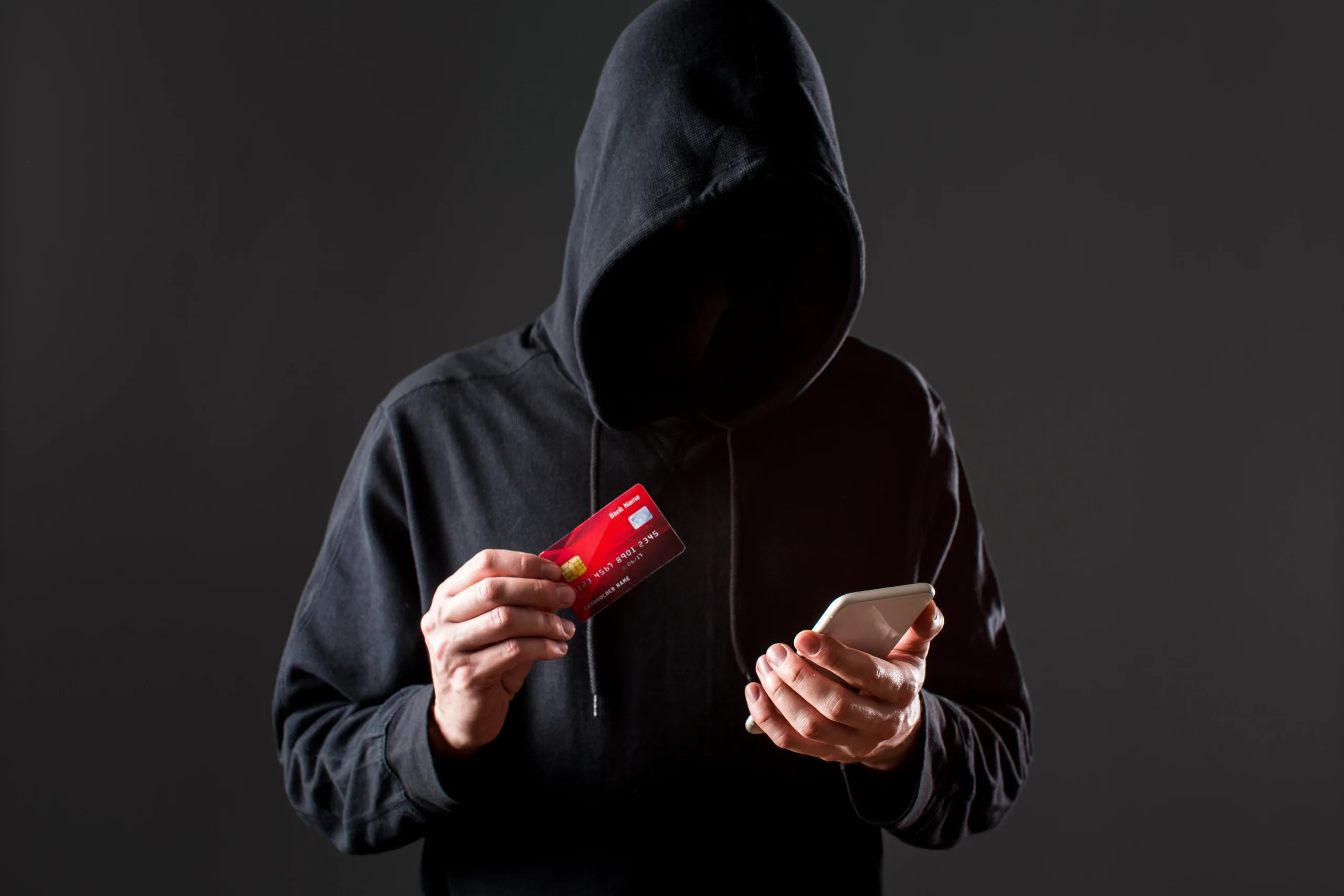 a men in a hoodie holding card and phone