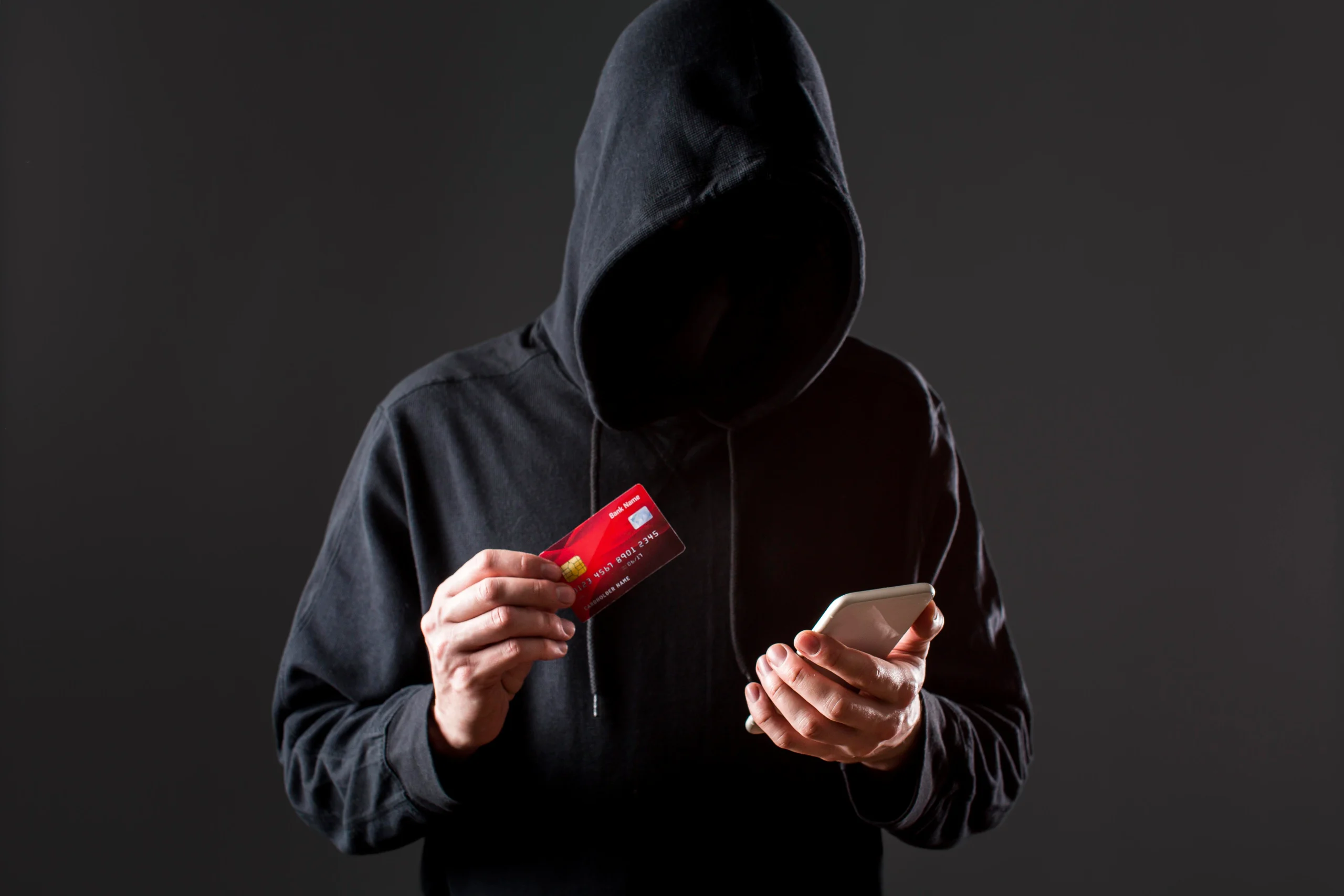 A men in a hoodie holding card and phone